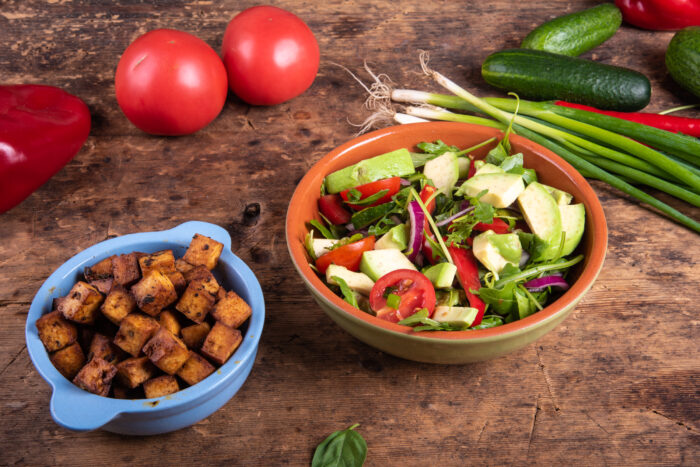 Fresh chopped vegetables and avocado in a bowl with soy balsamic dressing