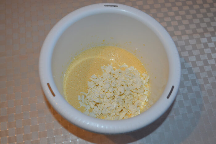 Adding cottage cheese to the egg and sugar mixture in the bowl