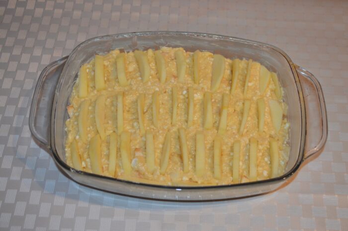 Apple slices neatly arranged on top of the unbaked cake