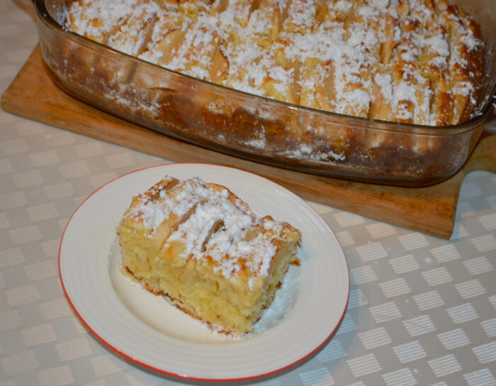 Baked apple and cottage cheese cake dusted with powdered sugar and sliced