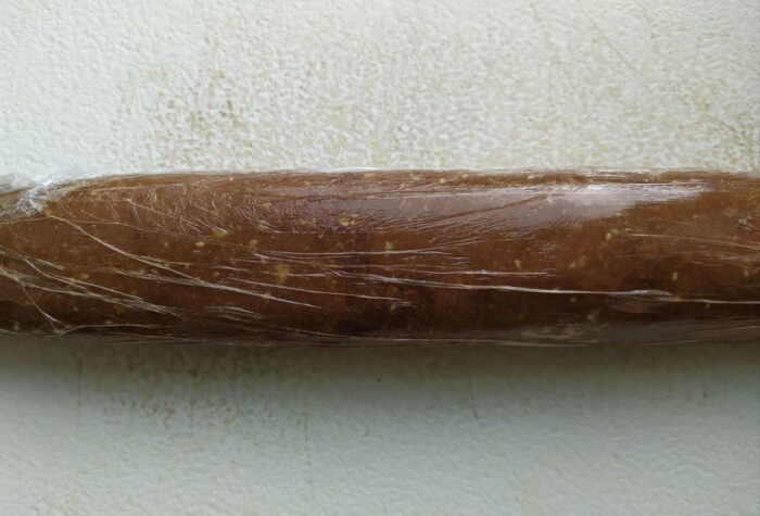 Chocolate salami mixture rolled tightly in plastic wrap into a log