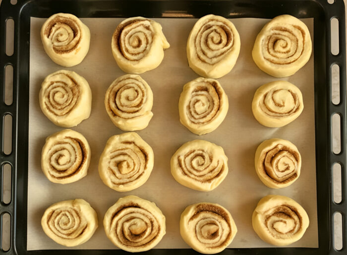 Cinnamon rolls arranged in a parchment-lined pan, ready to bake