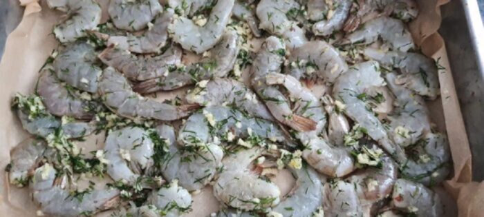 Marinated shrimp arranged in a single layer on a baking tray