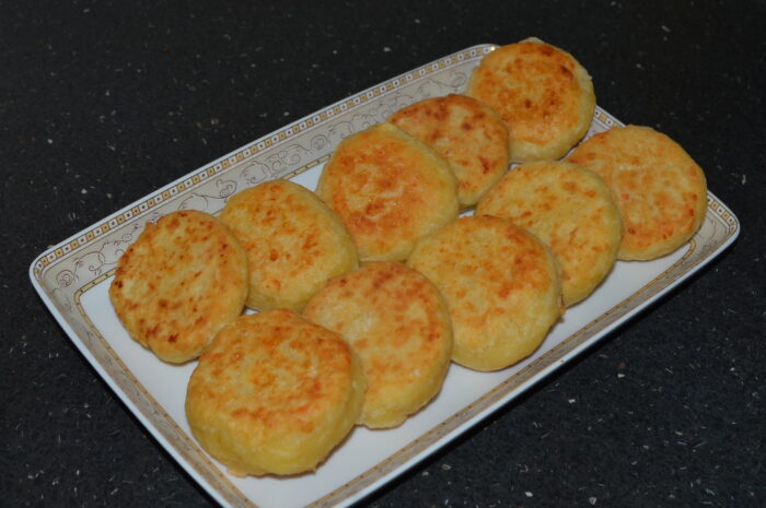 Golden-brown savory cheese fritters stacked on a plate ready to serve