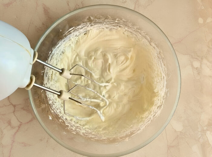 Cream cheese and butter frosting being whipped in a bowl