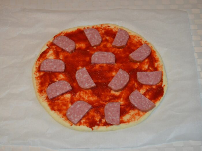 Salami slices arranged evenly on top of the pizza