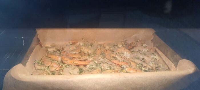 Shrimp baking in the oven on a parchment‑lined tray