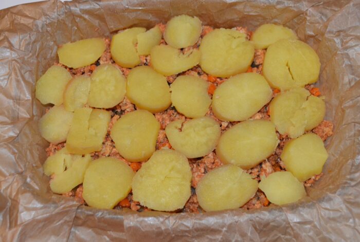 Second layer of sliced potatoes arranged over the meat filling