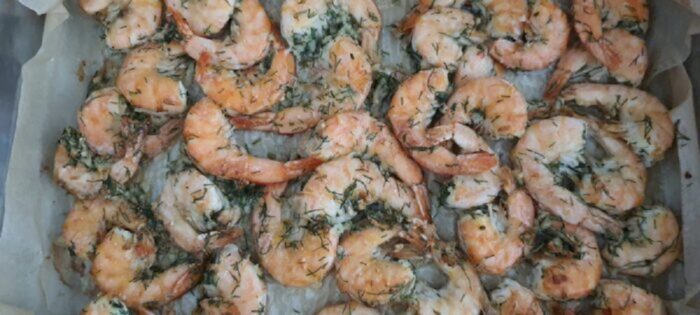 Removing the hot baking tray with roasted shrimp from the oven