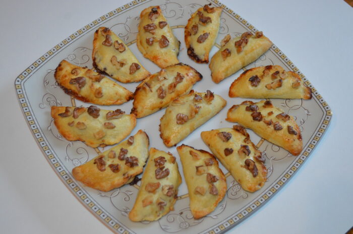 Plate of baked walnut and jam crescents arranged and ready to serve