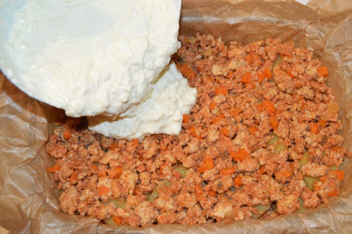 Creamy cheese and sour cream sauce poured over the top of the assembled moussaka