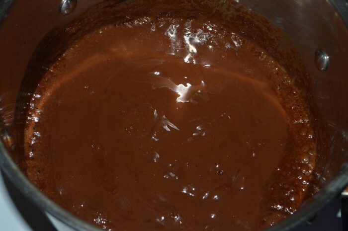 Silky chocolate glaze in a saucepan ready to pour over cake