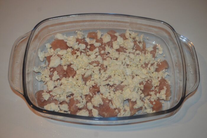 Cottage cheese being spooned over the chopped chicken breast