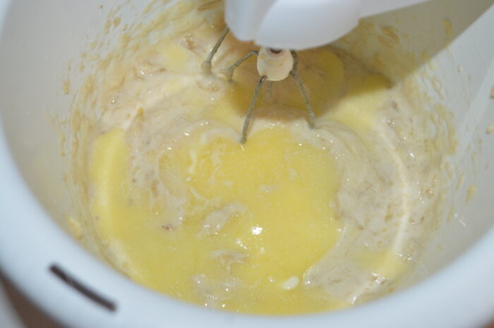 Melted butter being poured into a bowl of banana puree