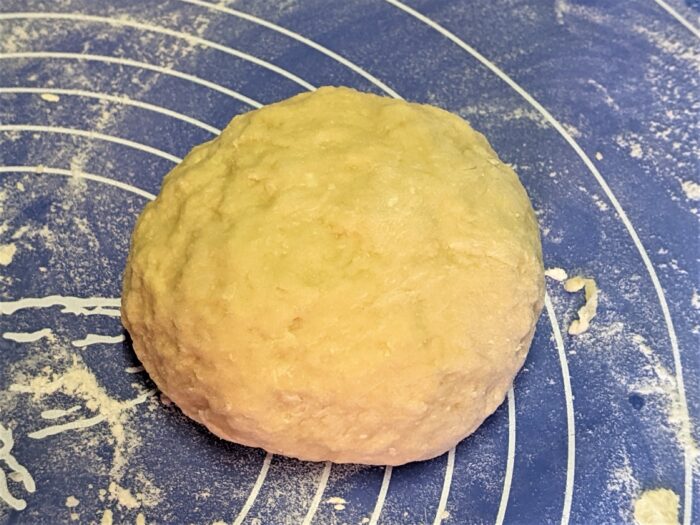 Smooth noodle dough resting in a bowl after kneading