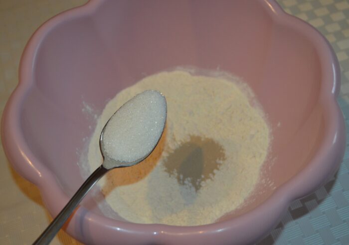 Sugar being added to the flour and yeast mixture