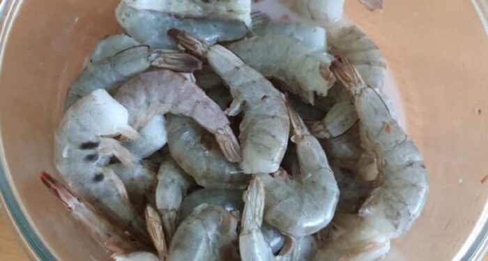 Rinsing thawed shrimp under cold water in a kitchen colander