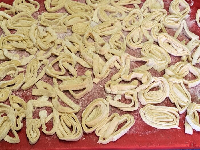 Thin homemade noodle sheet rolled and sliced into fine strips