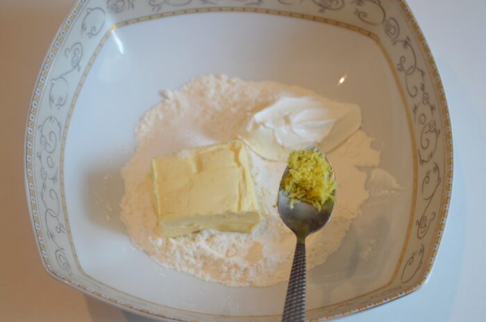 Fresh lemon zest being grated finely into the dough mixture