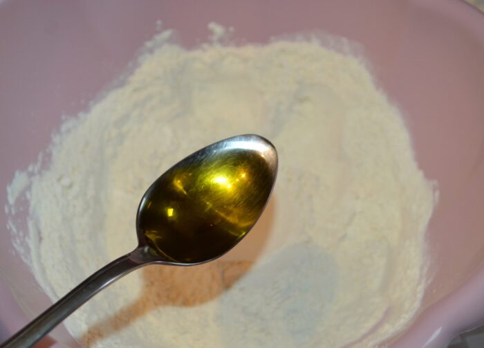 Olive oil being poured into the dry dough mixture