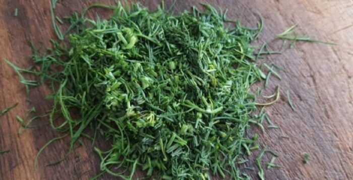 Finely chopped fresh dill on a wooden cutting board