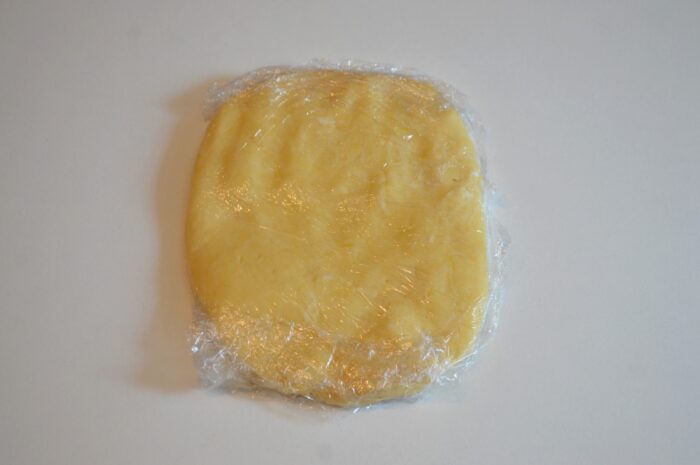 Dough wrapped in plastic wrap resting in the refrigerator