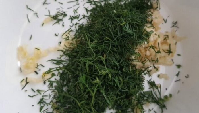 Mixing chopped garlic and dill together in a small bowl