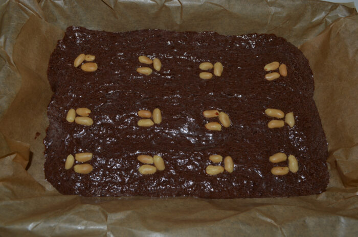 Brownie batter topped with chopped peanuts before baking