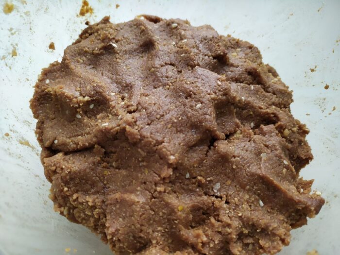 Chocolate biscuit mixture being kneaded by hand until smooth and cohesive
