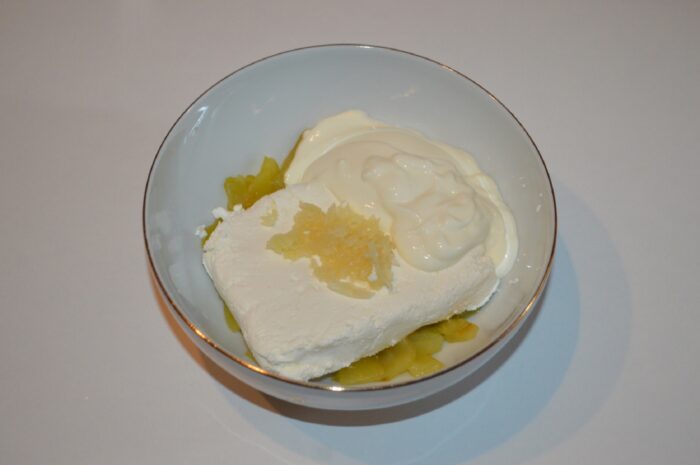 Greek yogurt being spooned into the bowl with cheese, pepper, and garlic
