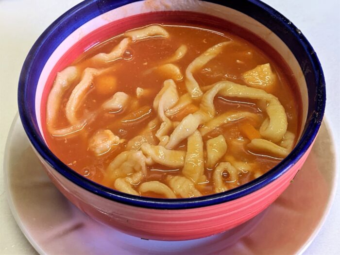 Homemade egg noodles boiling in tomato soup