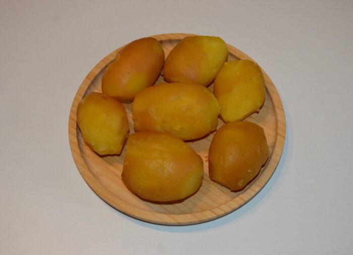 Boiled whole potatoes with skins on, cooling before peeling