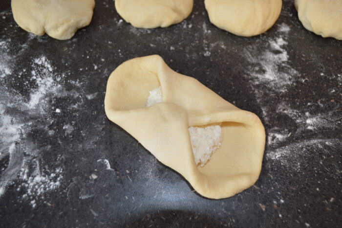 Manos uniendo las esquinas opuestas de la masa rellena